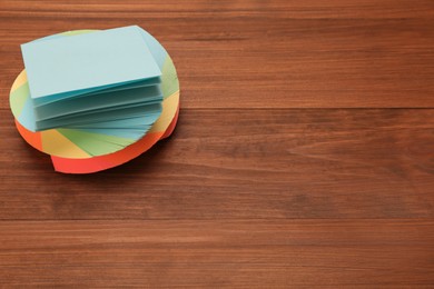 Stack of colorful stickers on wooden table, space for text
