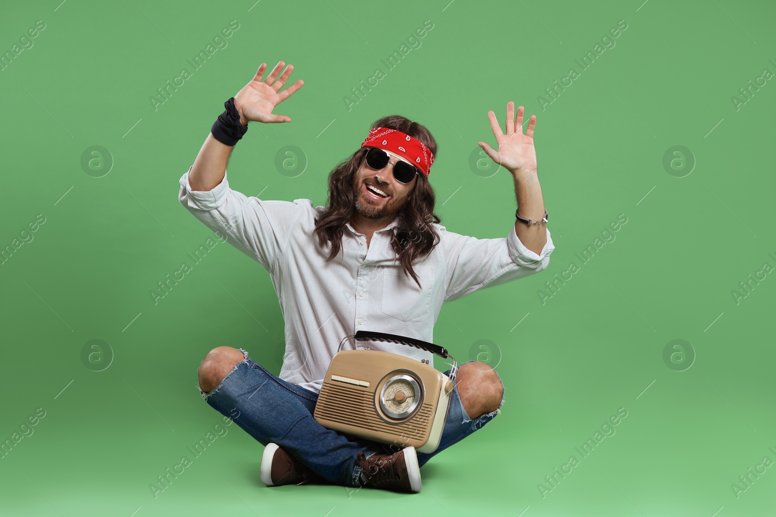 Photo of Stylish hippie man in sunglasses with retro radio receiver on green background