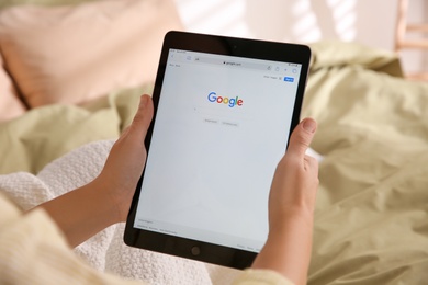 MYKOLAIV, UKRAINE - OCTOBER 31, 2020: Woman using Google search engine on tablet in bed, closeup