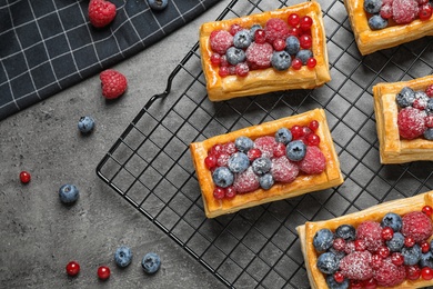 Photo of Fresh delicious puff pastry with sweet berries on grey table, flat lay. Space for text