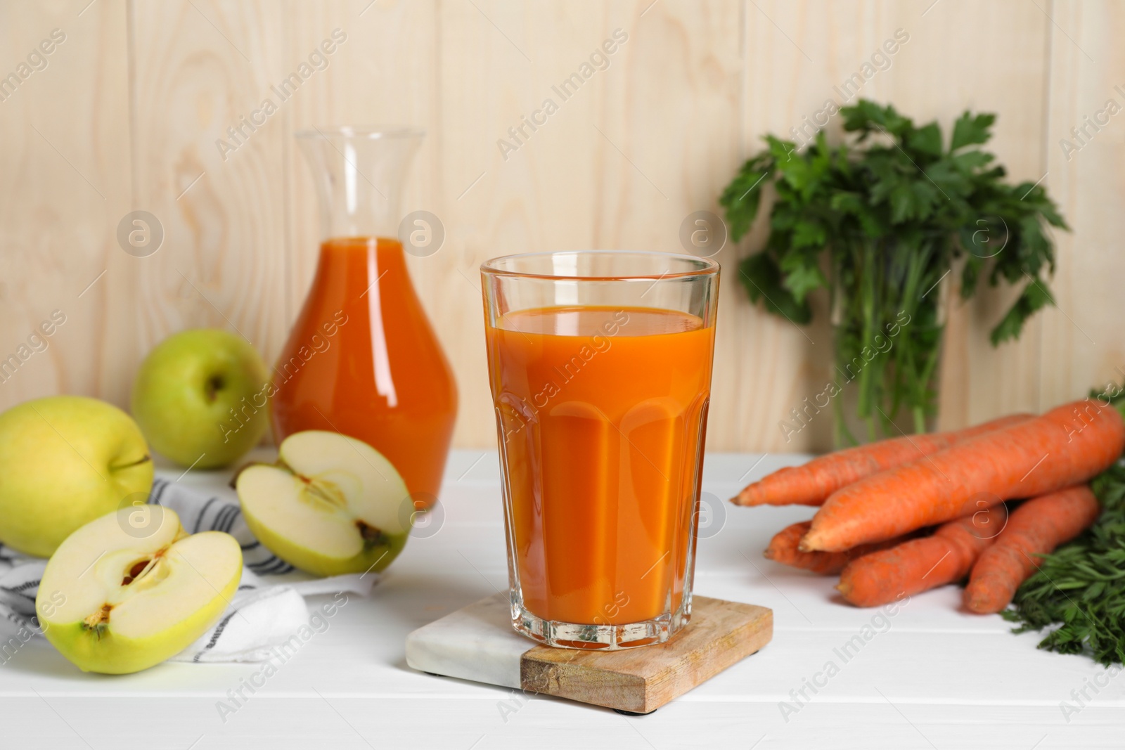 Photo of Tasty carrot juice and ingredients on white wooden table