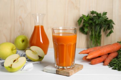 Photo of Tasty carrot juice and ingredients on white wooden table