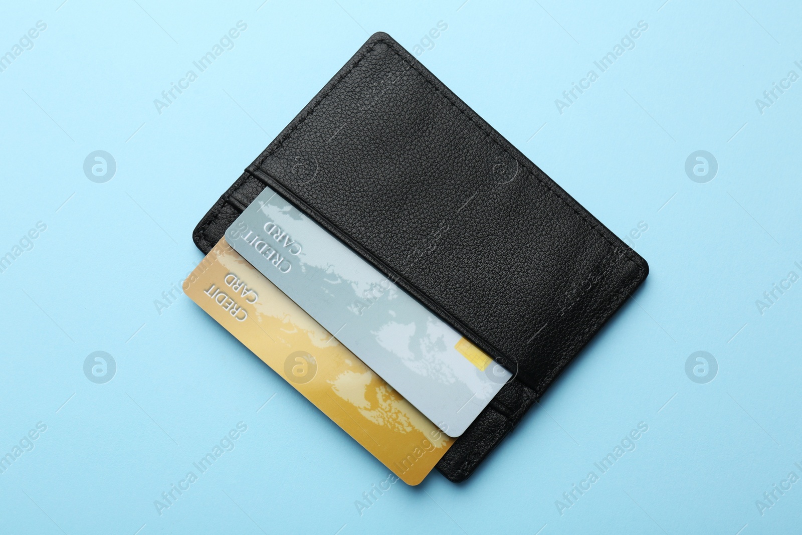 Photo of Leather card holder with credit cards on light blue background, top view