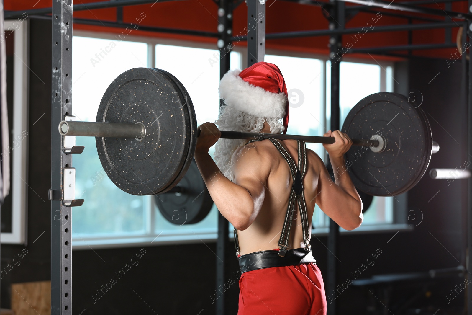 Photo of Young muscular man in Santa costume training at gym