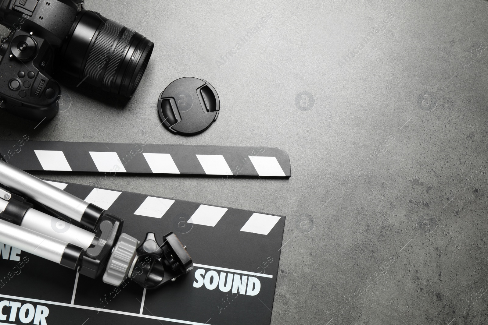 Photo of Clapboard, camera with tripod and space for text on grey background, flat lay. Video production industry