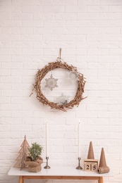 Photo of Console table with Christmas decoration near brick wall. Idea for festive interior