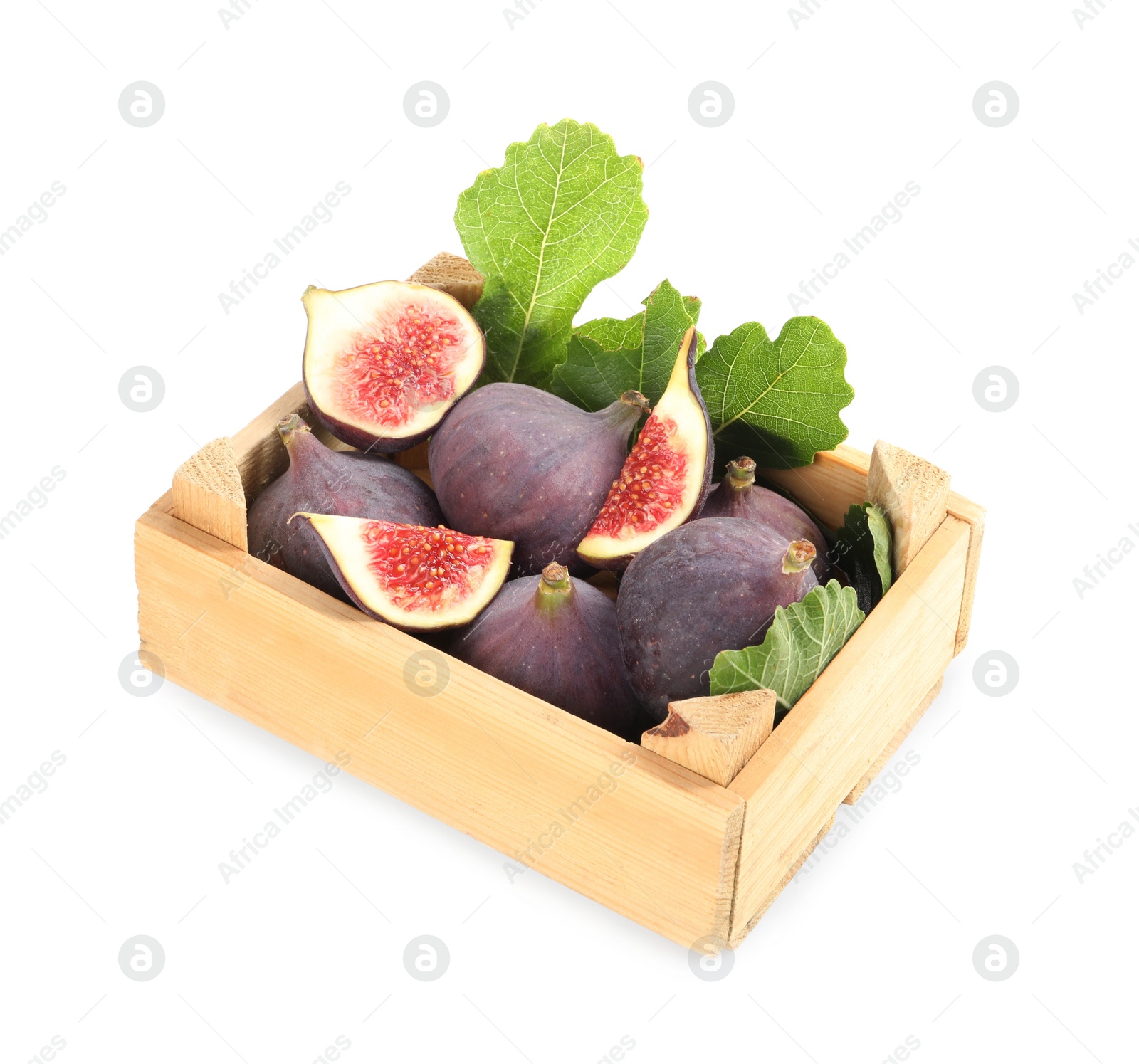 Photo of Whole and cut tasty fresh figs with green leaves in wooden crate on white background