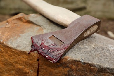 Photo of Axe with blood on stone outdoors, closeup