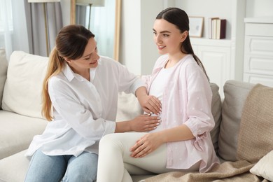 Photo of Doula taking care of pregnant woman on sofa at home. Preparation for child birth