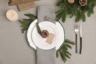 Photo of Festive place setting with beautiful dishware, cutlery and cone for Christmas dinner on grey table, flat lay