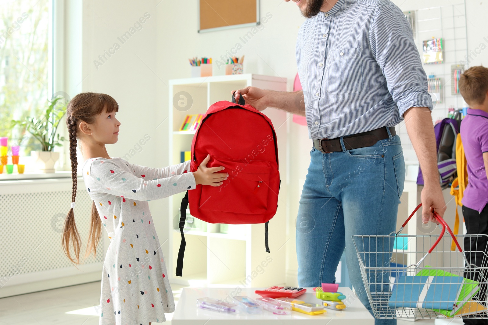 Photo of Little girl choosing school supplies with father in stationery shop