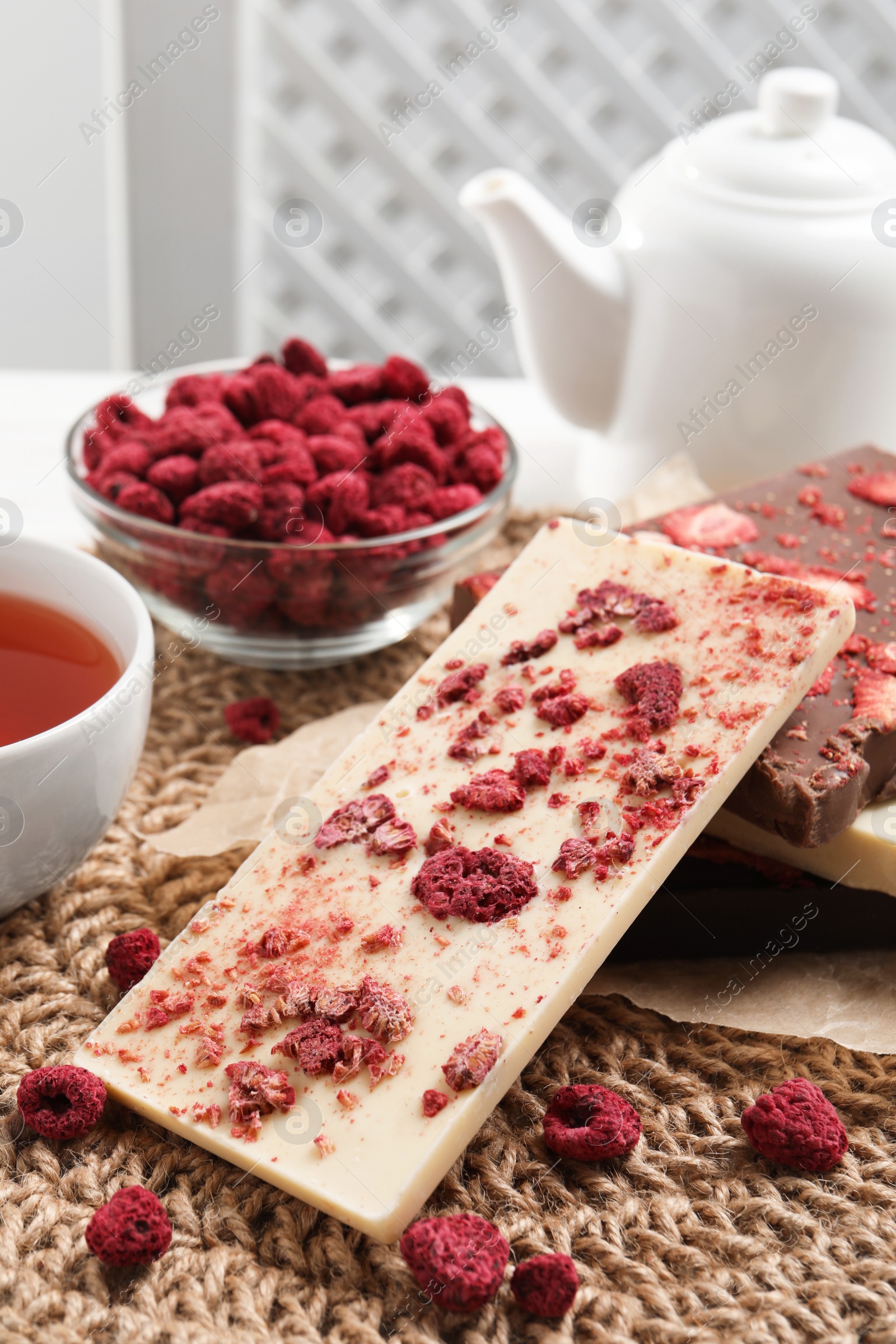 Photo of Different chocolate bars with freeze dried fruits on wicker mat