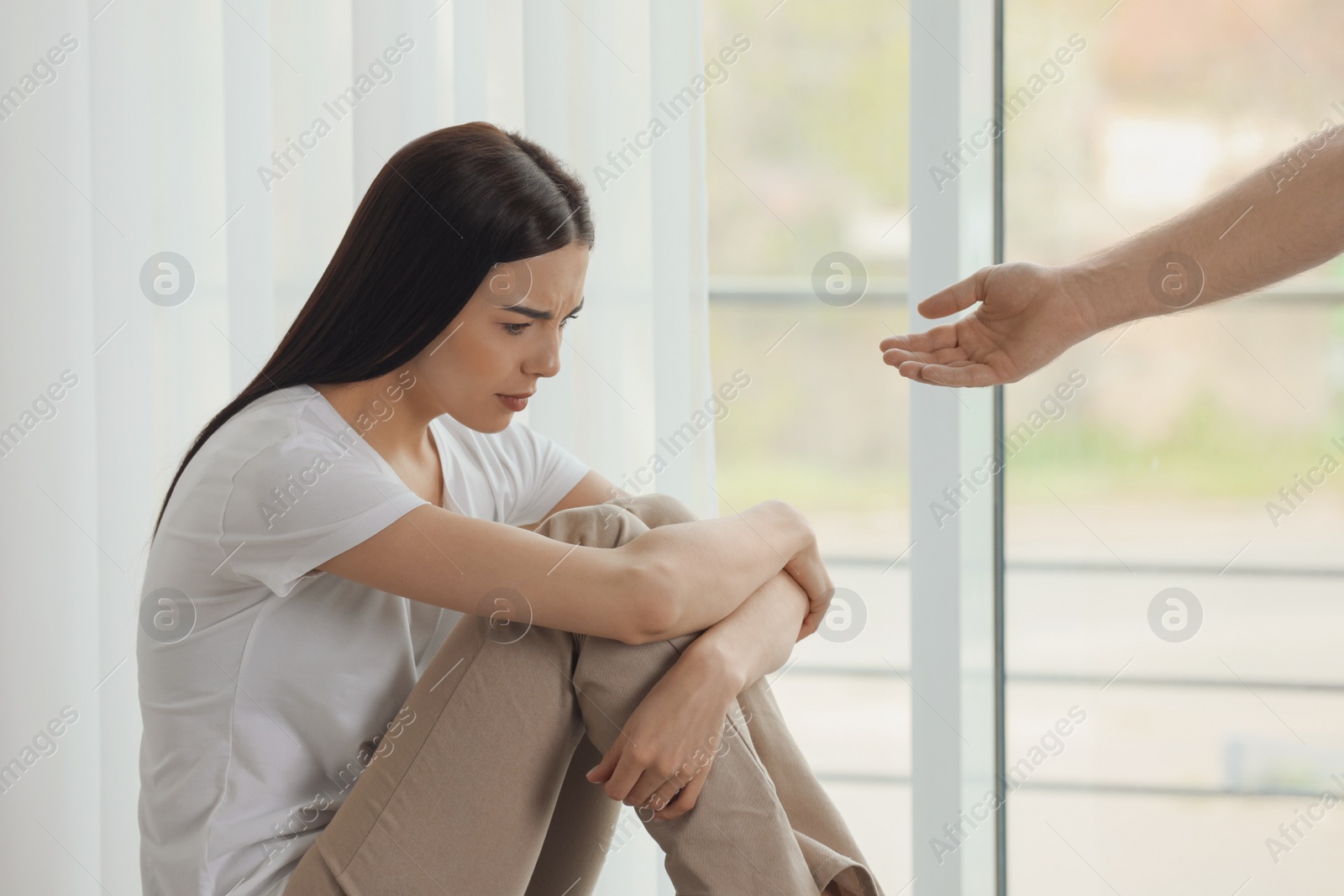 Photo of Man offering hand to depressed woman indoors