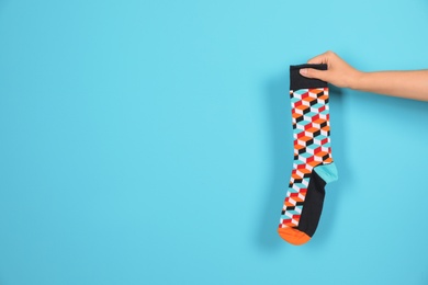 Photo of Woman holding bright sock and space for design on color background