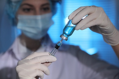 Doctor filling syringe with vaccine against Covid-19 in laboratory, focus on hands