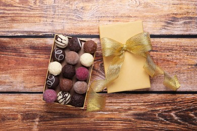 Photo of Open box with delicious chocolate candies on wooden table, top view