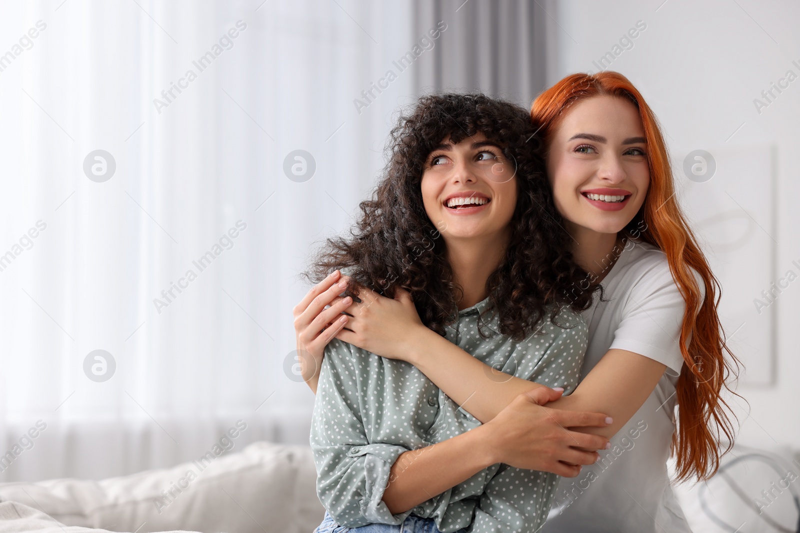 Photo of Portrait of happy young friends hugging at home, space for text