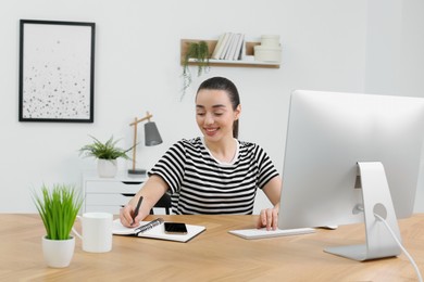 Home workplace. Happy woman working at wooden desk in room