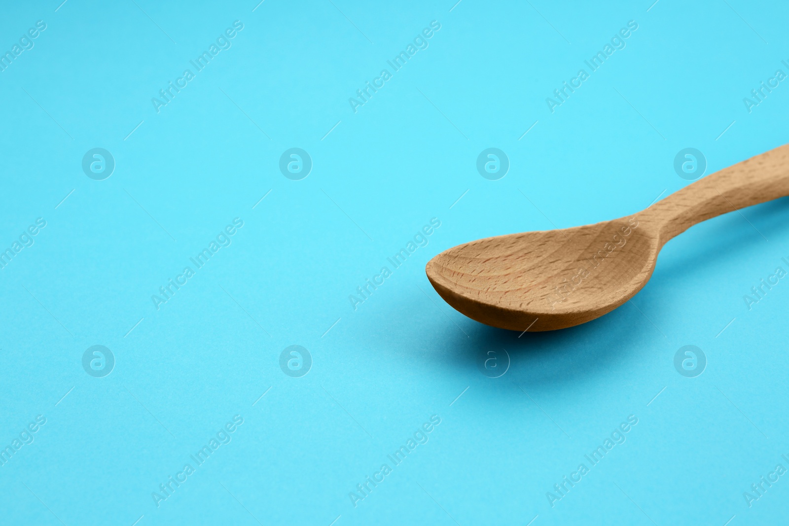 Photo of Clean empty wooden spoon on blue background, space for text