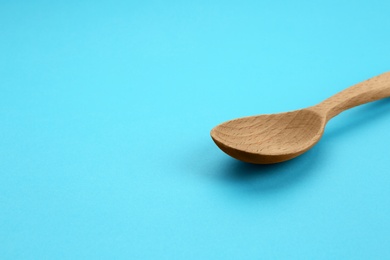 Clean empty wooden spoon on blue background, space for text