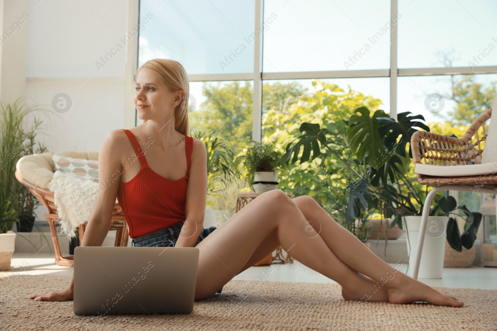 Photo of Young woman with laptop sitting on floor at indoor terrace