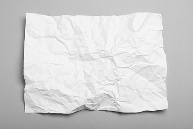 Photo of Sheet of white crumpled paper on grey background, top view