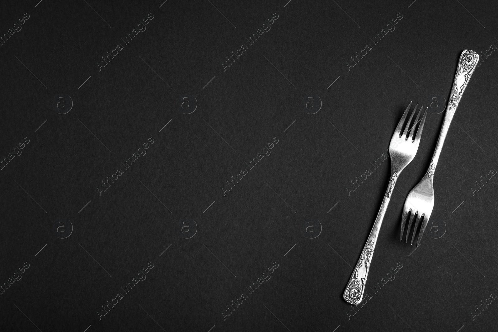 Photo of Silver forks on black background, flat lay with space for text