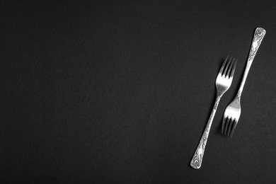 Silver forks on black background, flat lay with space for text