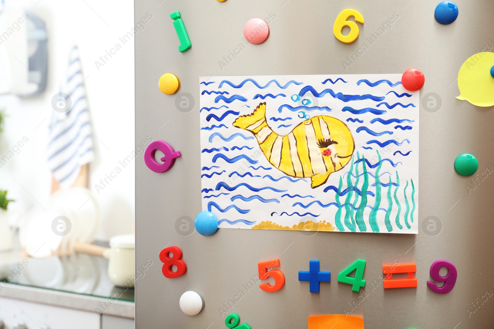 Photo of Child's drawing and magnets on refrigerator door in kitchen