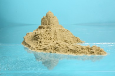 Photo of Pile of sand with sultan's palace near rippled water against light blue background. Beautiful castle
