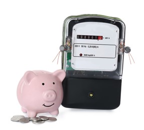 Photo of Electricity meter, pink piggy bank and coins on white background