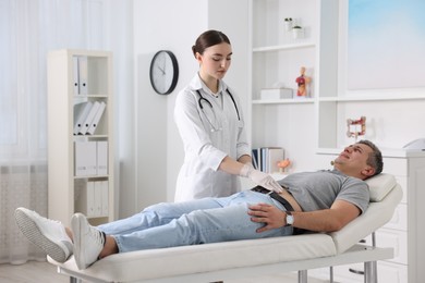 Photo of Gastroenterologist examining patient with stomach pain on couch in clinic