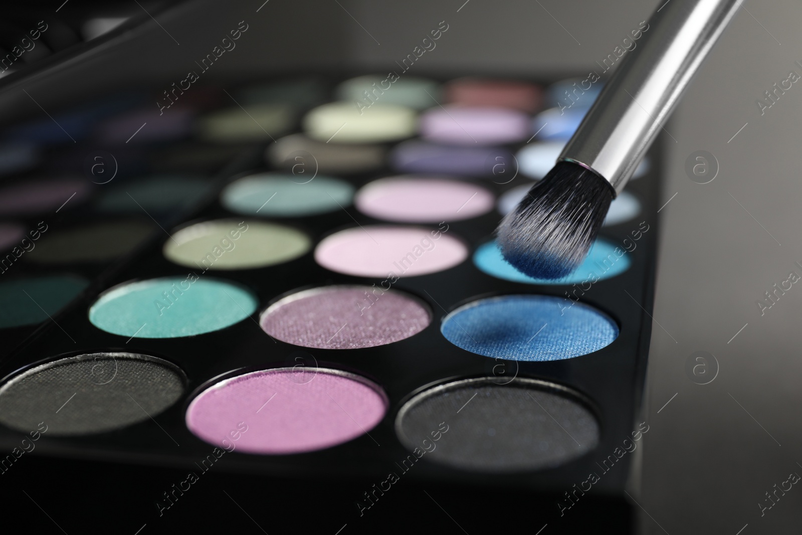 Photo of Colorful eyeshadow palette with brush, closeup view