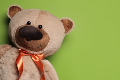 Photo of Cute teddy bear on light green background, top view. Space for text