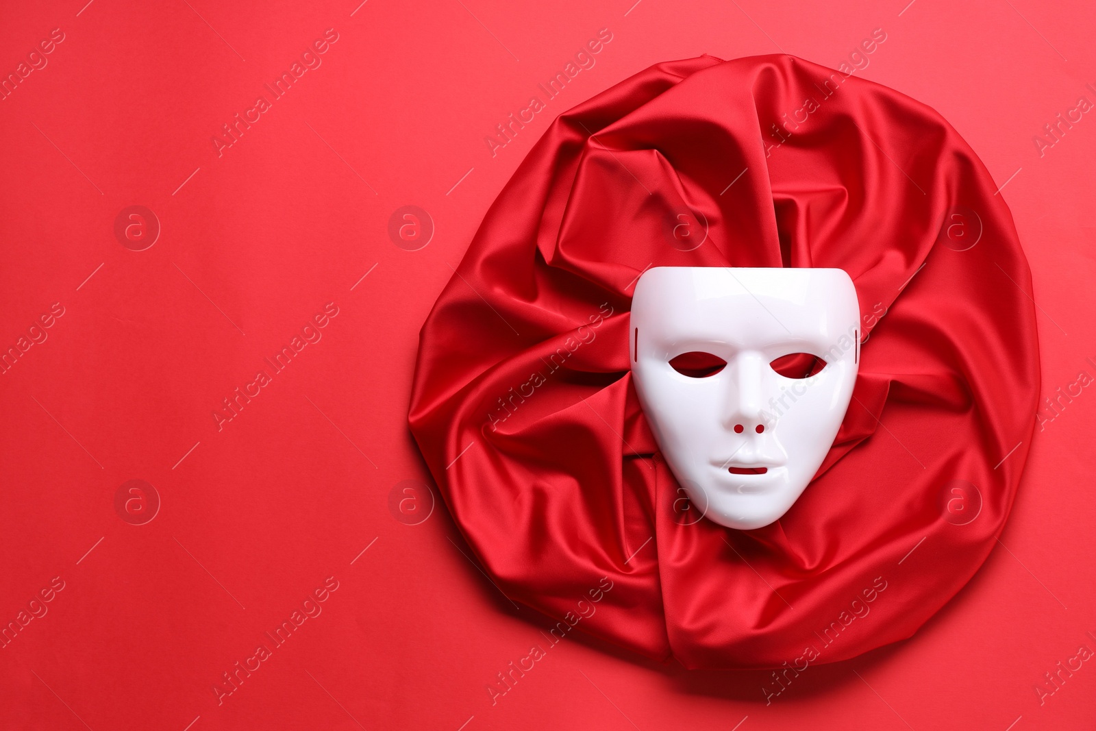 Photo of Theater arts. White mask and fabric on red background, top view. Space for text