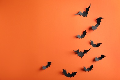 Paper bats on orange background, flat lay with space for text. Halloween decor