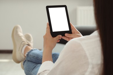 Photo of Young woman using e-book reader at home, closeup