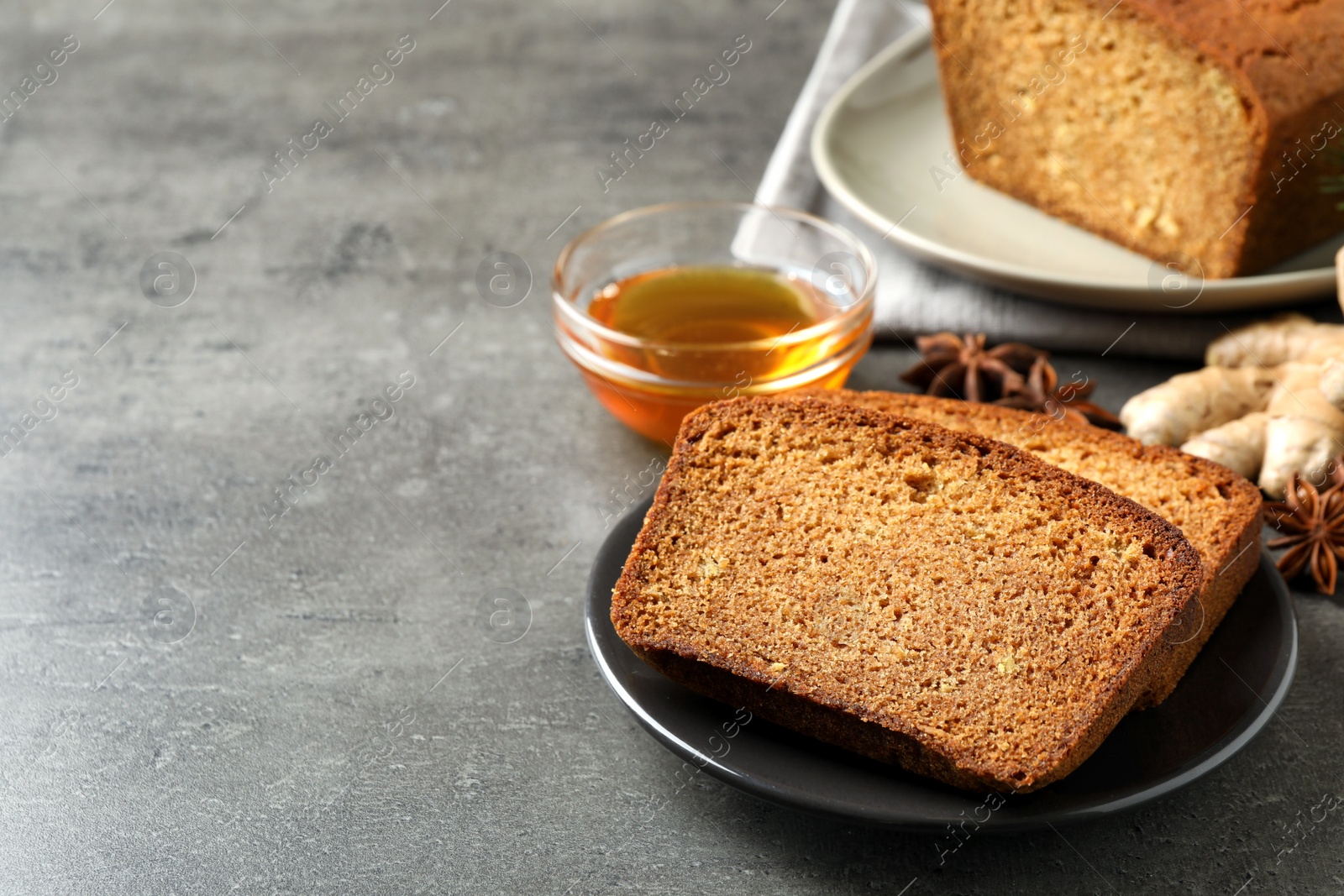 Photo of Fresh gingerbread cake slices served on grey table, space for text