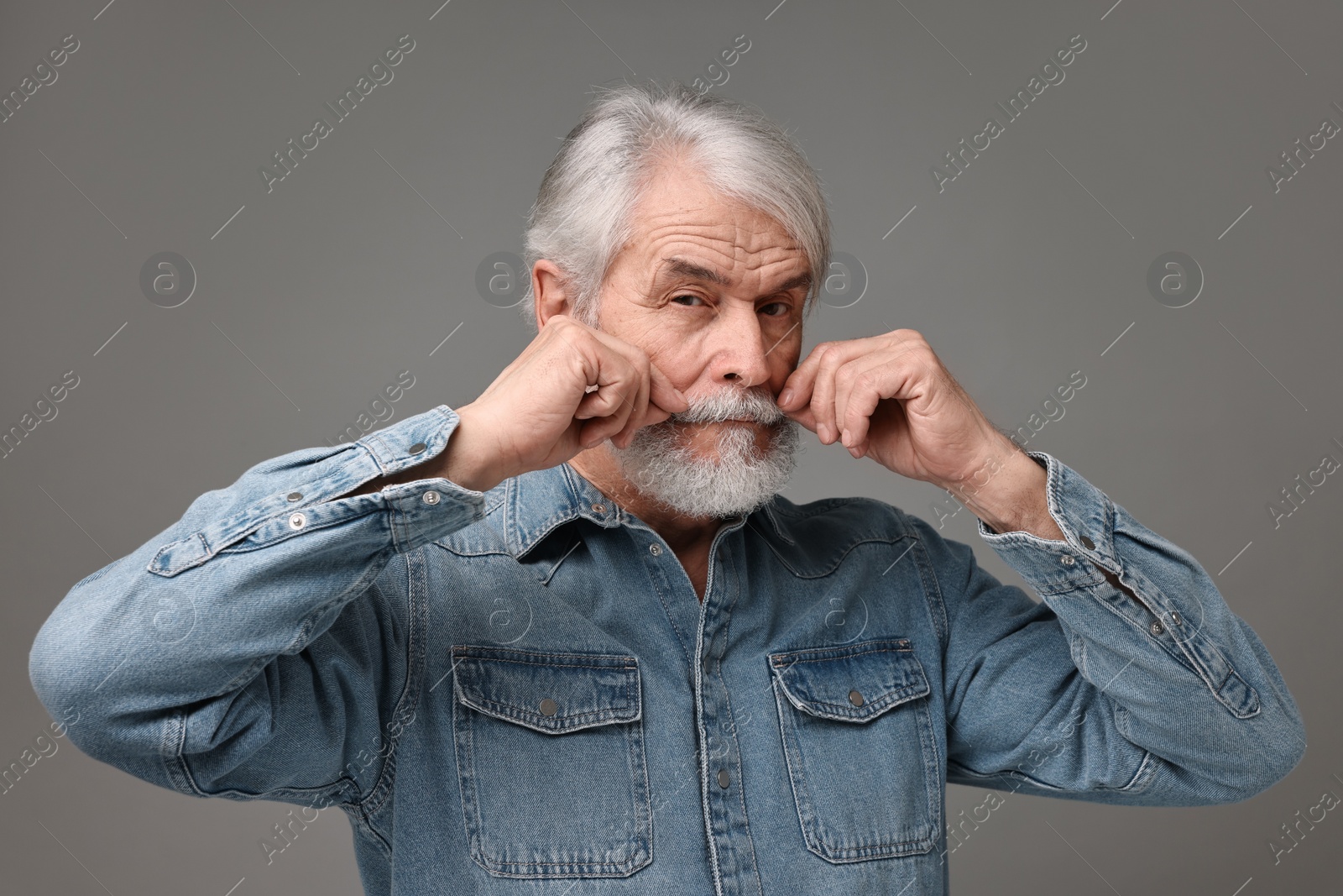 Photo of Senior man touching mustache on grey background