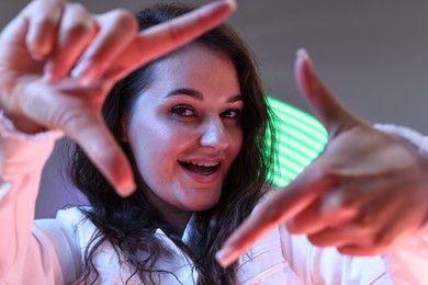 Portrait of beautiful young woman on color background with neon lights