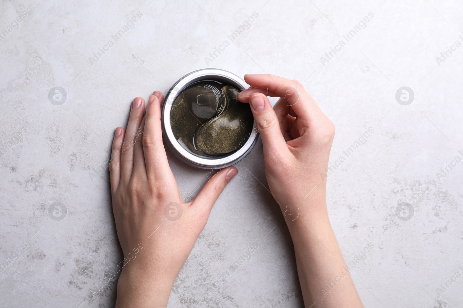 Photo of Woman with package of under eye patches at light table, top view. Cosmetic product