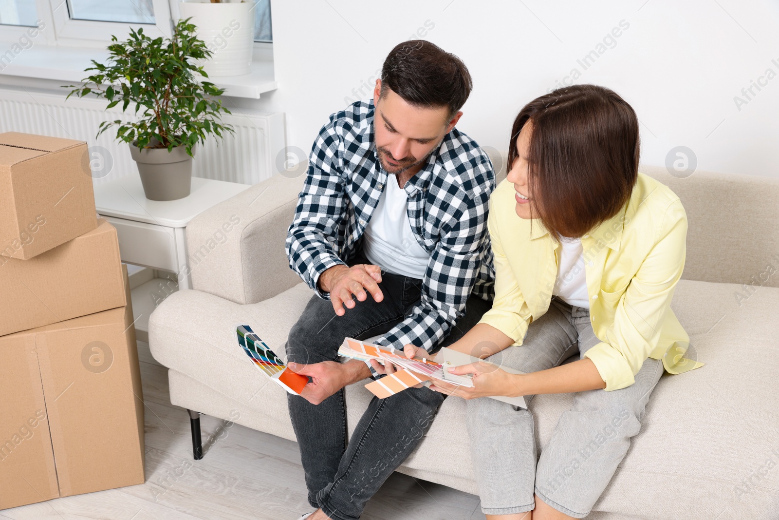 Photo of Happy couple choosing colors in new apartment. Moving day