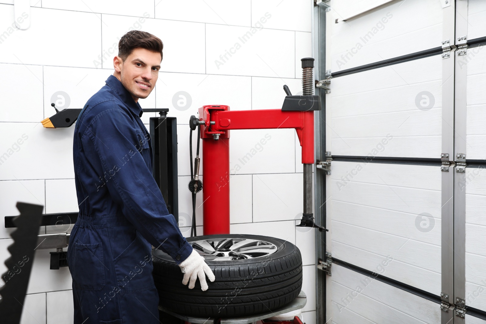 Photo of Man working with tire fitting machine at car service