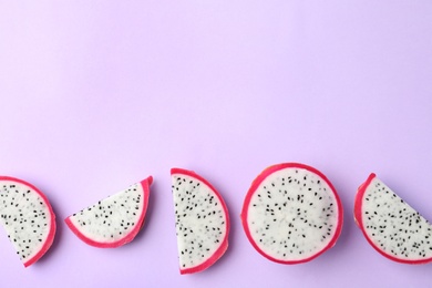 Slices of delicious dragon fruit (pitahaya) on violet background, flat lay. Space for text