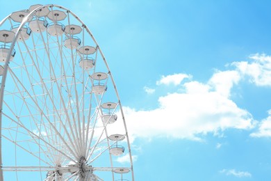Photo of Large white observation wheel against blue cloudy sky, space for text