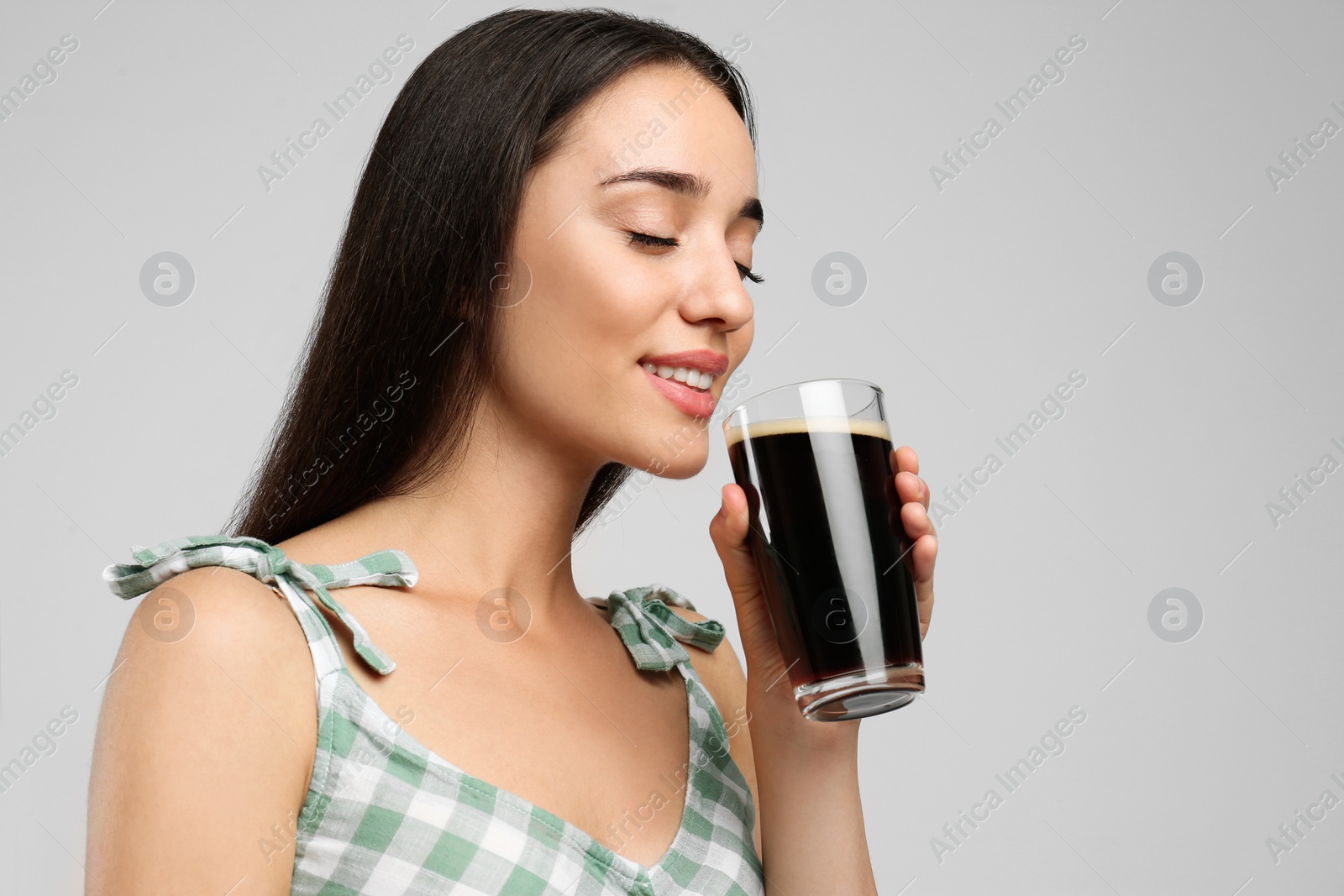 Photo of Beautiful woman with cold kvass on light grey background. Traditional Russian summer drink