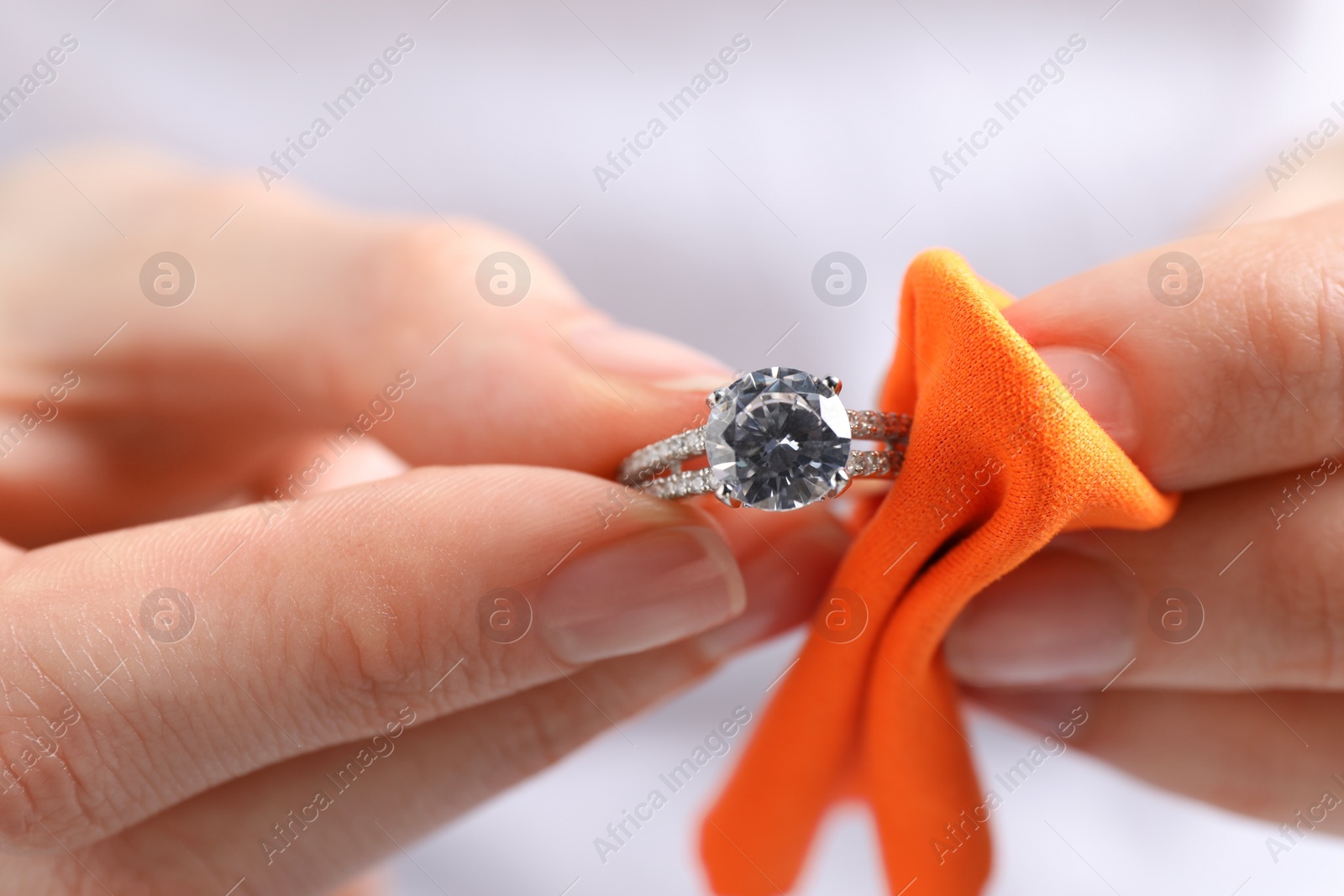 Photo of Jeweler cleaning diamond ring with microfiber cloth, closeup