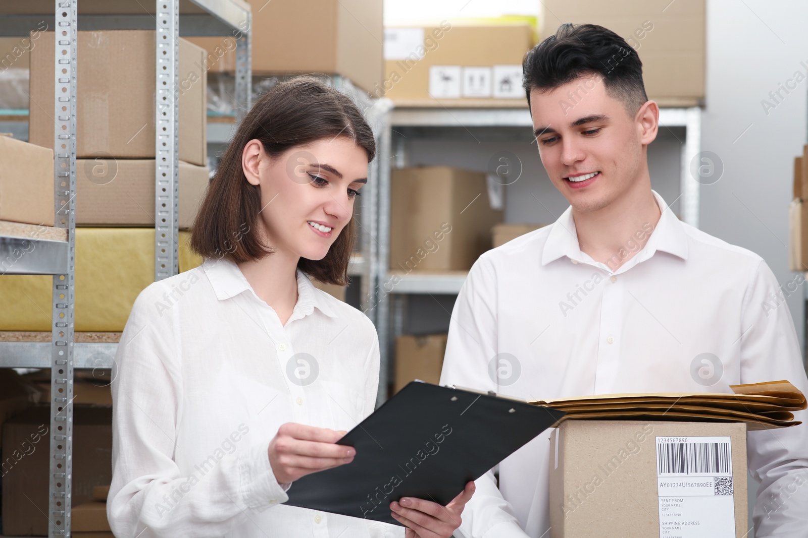 Photo of Post office workers checking parcel barcode near rack indoors