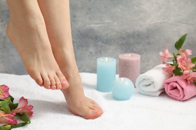 Photo of Woman with neat toenails after pedicure procedure on white terry towel, closeup