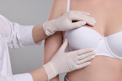 Mammologist checking woman's breast on gray background, closeup